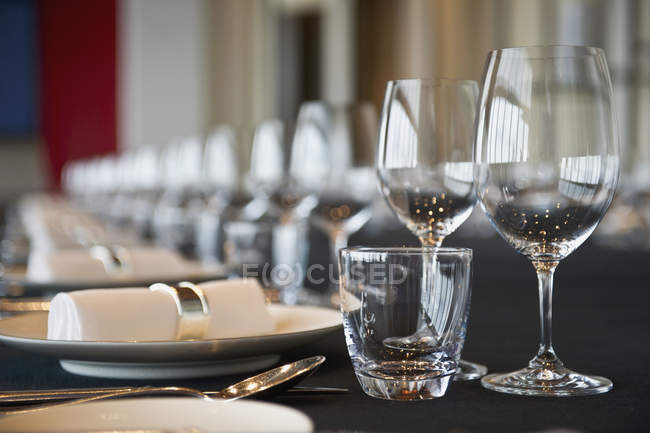 Elegant place settings on long dining table — Stock Photo