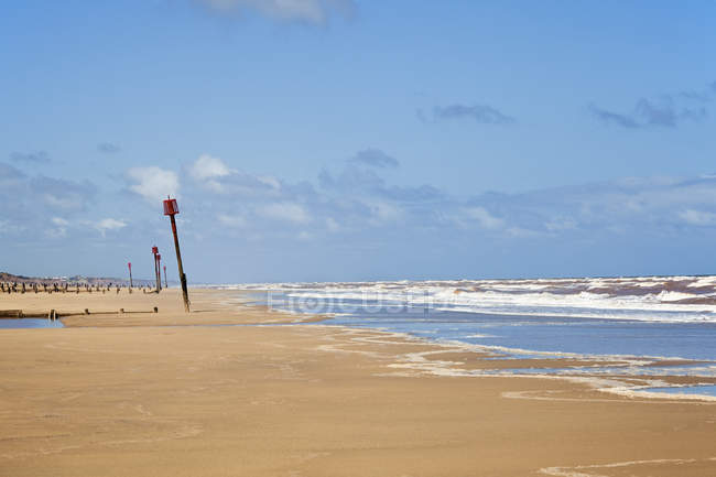 Spiaggia di sabbia con frangiflutti in distanza — Foto stock