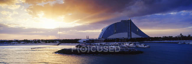 Jumeirah beach hotel at sunrise with boats on water, Dubai, United Arab Emirates — Stock Photo