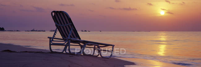 Beach lounger on sand by water at sunrise, Playa del Carmen, Quintana Roo, Mexico — Stock Photo