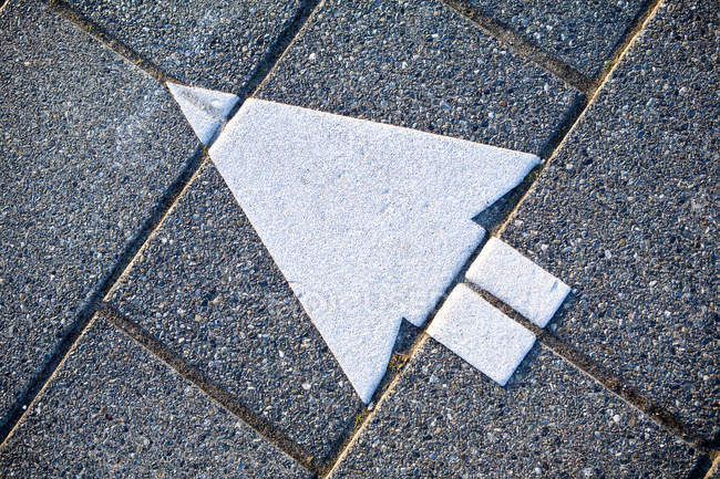 Flecha direccional en el suelo gris, primer plano - foto de stock