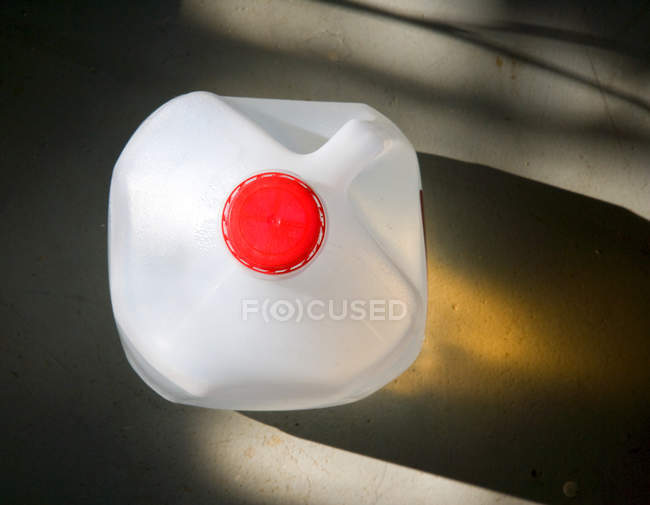 Vista de ángulo alto de la jarra de agua de plástico galón con tapa roja - foto de stock