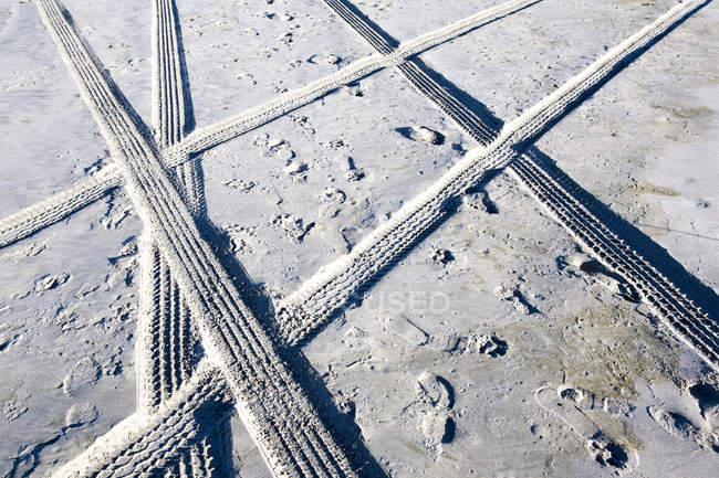 Pistas de pneus e pegadas na areia, quadro completo — Fotografia de Stock
