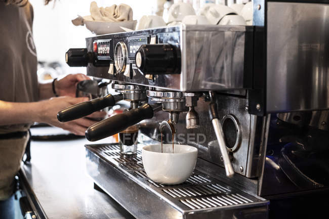 Mãos de barista fêmea fazendo cappuccino usando máquina de café expresso comercial . — Fotografia de Stock