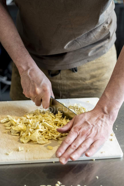 Köchin steht in Küche und schneidet getrocknete Apfelscheiben mit Messer. — Stockfoto