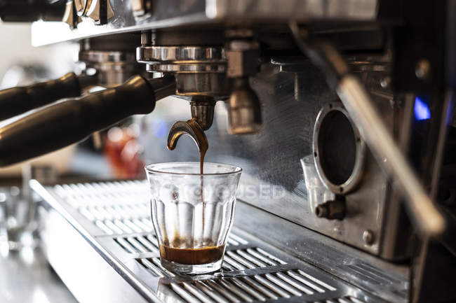 Nahaufnahme Kaffee, der in Glas auf kommerzieller Espressomaschine gegossen wird. — Stockfoto