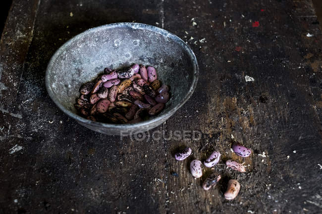 Nahaufnahme einer grauen Metallschale mit violett gesprenkelten Bohnen auf einem Holztisch. — Stockfoto
