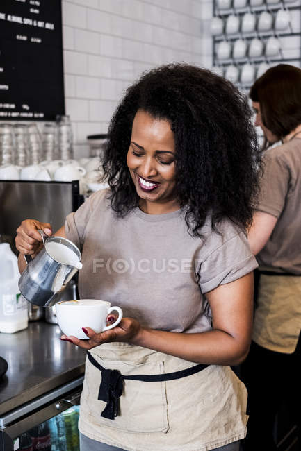 Barista femenina preparando una taza de café en la cafetería . - foto de stock