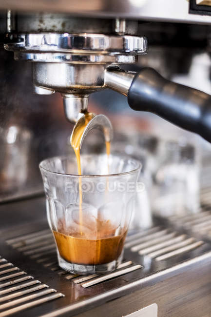 Nahaufnahme einer kommerziellen Espressomaschine im Café, die Kaffee in Glas gießt. — Stockfoto