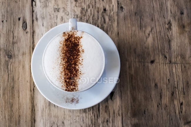 Vista superior da xícara de café no café, cappuccino com topo espumoso e pó de chocolate polvilhado . — Fotografia de Stock