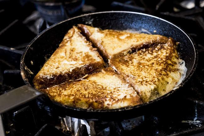 Frying pan on hob with eggy bread sandwiches fried. — Stock Photo
