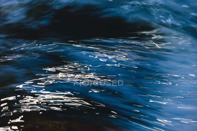 Primo piano astratto dell'acqua fluente del fiume con riflesso luminoso sulla superficie
. — Foto stock