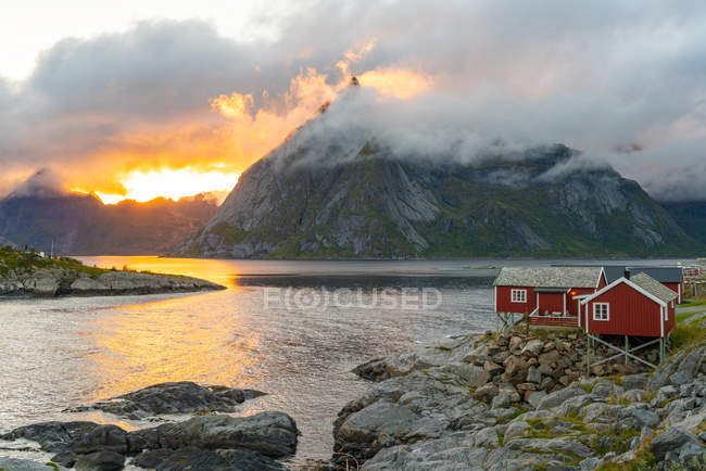 Низькі хмари закрученого раунду і охоплюють гори, малі традиційні будинки робу на берегової лінії, Лофотенских островів, Норвегія, Європа. — стокове фото