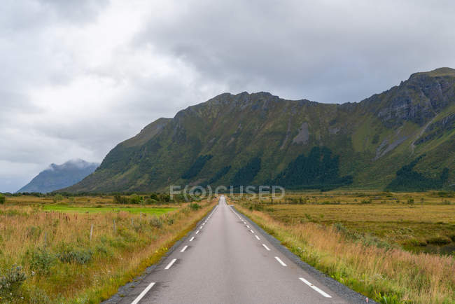 Strada dritta attraverso le montagne nel paesaggio nelle Isole Lofoten, Norvegia, Europa . — Foto stock