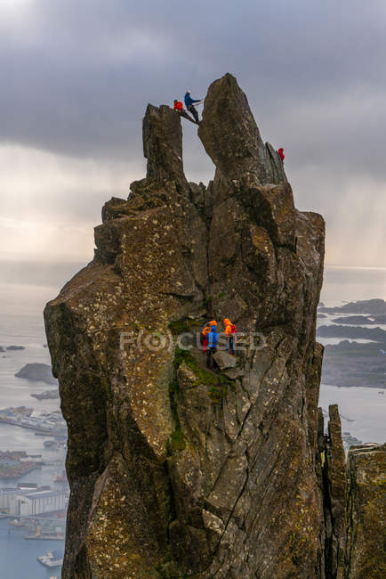 Gruppo di persone che si arrampicano sul pinnacolo frastagliato Svolvaer Goat, Lofotens, Norvegia, Europa . — Foto stock