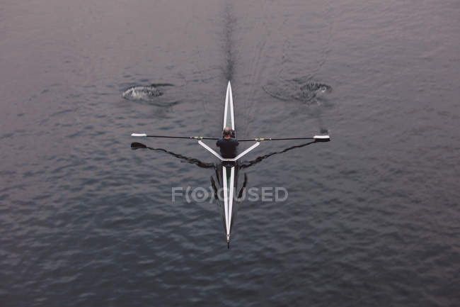 Vista aérea de reoarsman en un solo barco del scull en el movimiento medio del agua calma, desenfoque del movimiento . - foto de stock