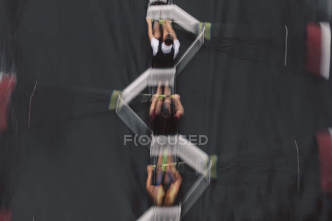 Blurred motion overhead view of rowing crew in sculling boat on water. — Stock Photo