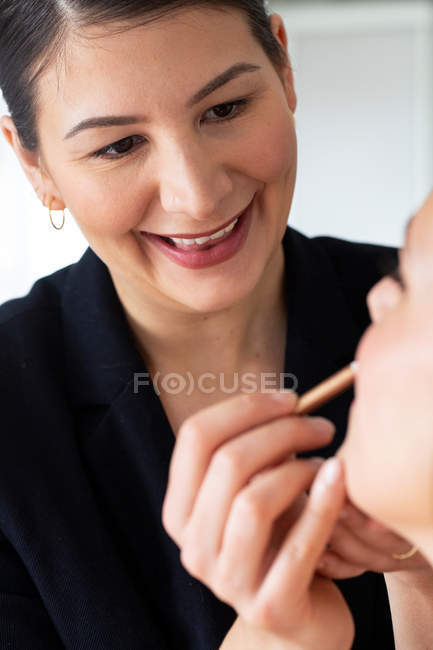 Truccatore professionista che applica cosmetici al lavoro, creando look per donna . — Foto stock