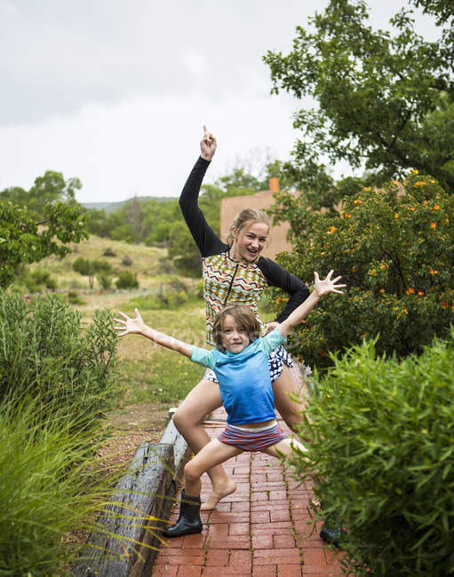 Старшеклассник с сестрой-подростком, танцующей под дождем . — стоковое фото