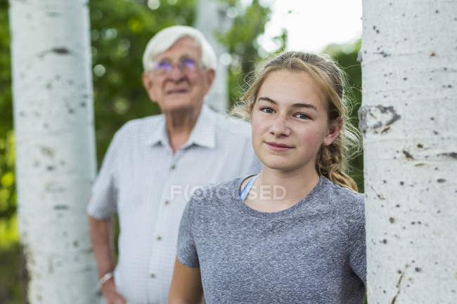 Abuelo y nieta juntos entre los árboles en el jardín . - foto de stock