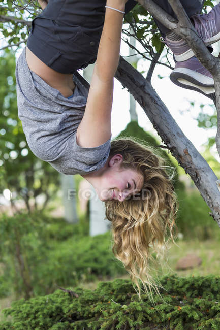 Ragazza bionda adolescente appesa a testa in giù da albero . — Foto stock