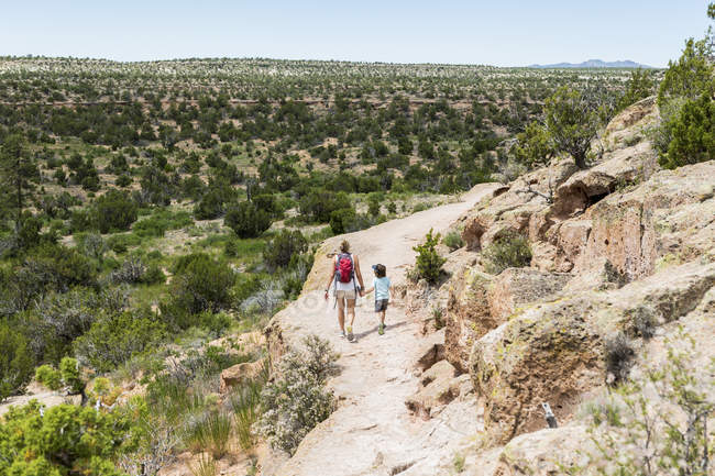 Madre e hijo pequeño caminando por el camino, Ruinas Tsankawi, Nuevo México, EE.UU. - foto de stock