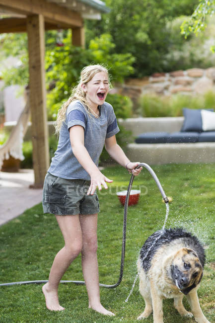 Blondes Teenager-Mädchen wäscht Hund auf grünem Rasen. — Stockfoto