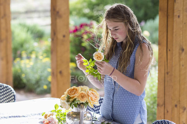 Ragazza bionda adolescente che organizza rose dal giardino formale . — Foto stock