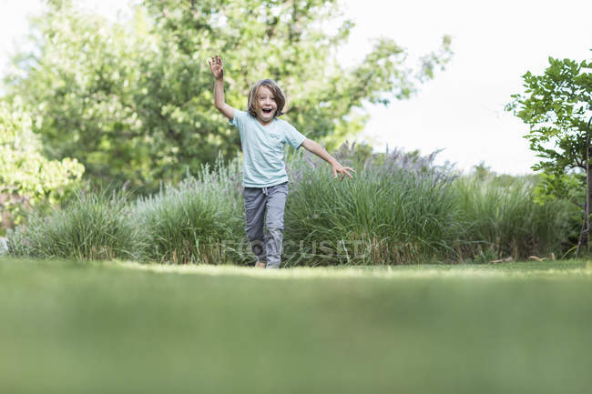 Happy little boy running on green lawn. — Stock Photo