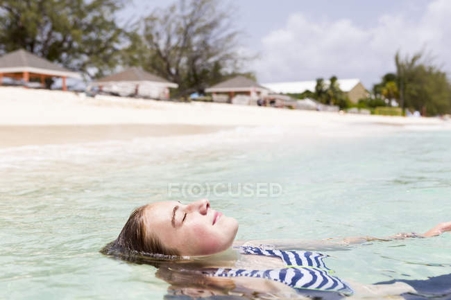 Loira adolescente flutuando na água do oceano . — Fotografia de Stock
