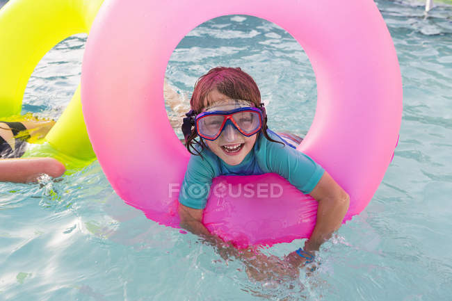 Menino da idade elementar brincando na piscina com flutuador colorido . — Fotografia de Stock