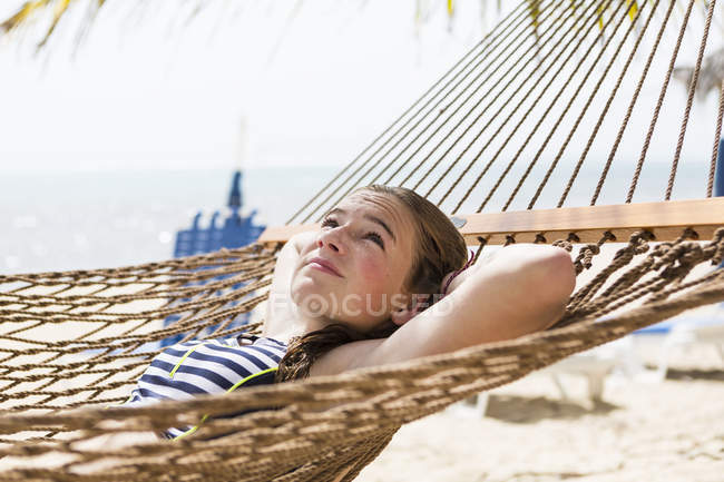 Loira adolescente relaxante na rede na praia . — Fotografia de Stock