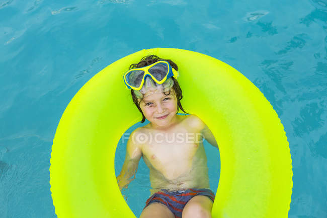 Lächelnder Vorschuljunge im bunten Schwimmen auf dem Wasser. — Stockfoto