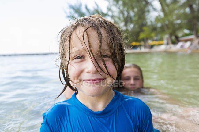 Smiling preschooler boy in wet shirt in ocean water. — Stock Photo