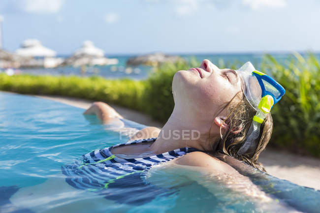 Loira adolescente relaxante na piscina infinita . — Fotografia de Stock