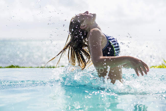 Blonde teenage in infinity pool tossing wet hair. — Stock Photo