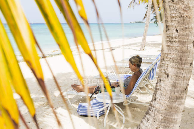 Femme cadre adulte utilisant un ordinateur portable sur la plage, Grand Cayman Island — Photo de stock
