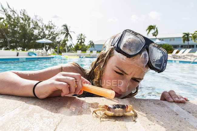 Teenage girl looking at crawling crab near pool. — Stock Photo