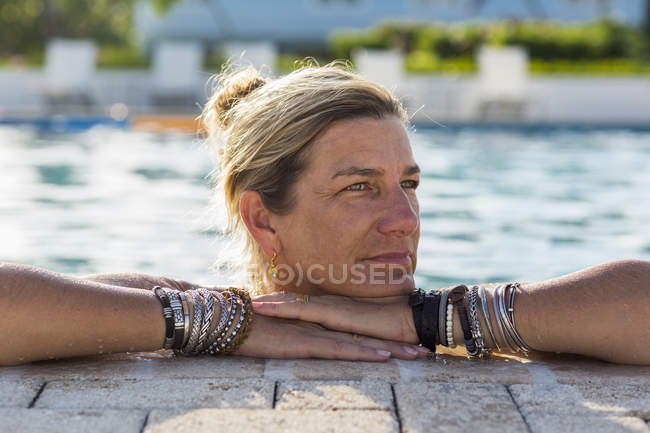 Adult woman leaning on side of swimming pool — Stock Photo