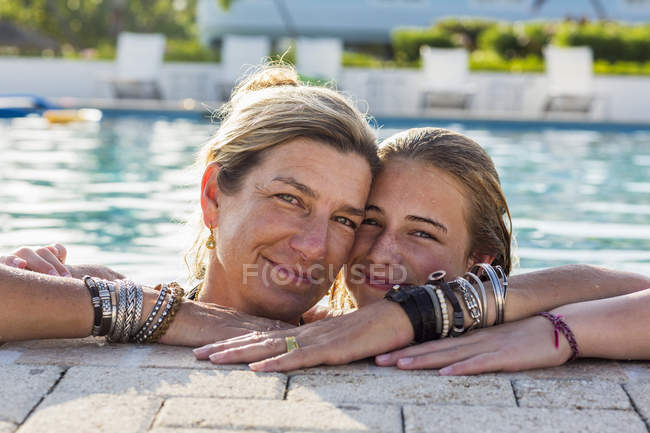 Madre con hija adolescente en la piscina sonriendo . - foto de stock