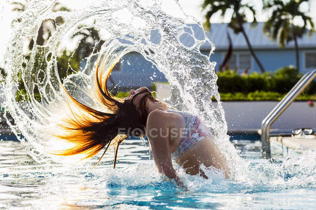 Adolescente jetant les cheveux mouillés dans la piscine . — Photo de stock
