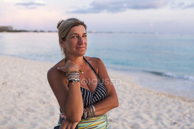 Erwachsene Frau blickt in die Kamera bei Sonnenuntergang an der Küste des Ozeans, Grand Cayman Island — Stockfoto