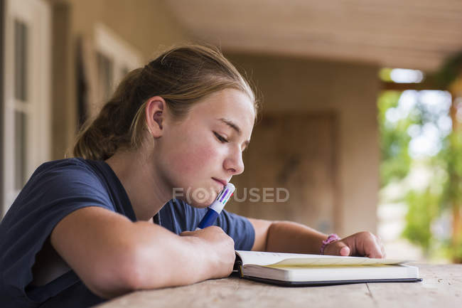 Adolescente lecture et écriture dans le journal intime à la maison — Photo de stock