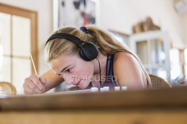 Adolescente em casa usando fones de ouvido como pintura — Fotografia de Stock