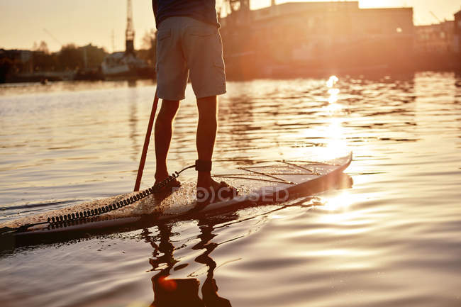Mann steht im Morgengrauen auf Tretbrett auf Fluss, beschnitten — Stockfoto