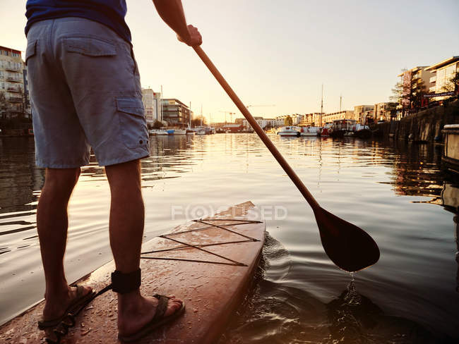 Homem de pé em paddleboard no rio ao amanhecer, cortado — Fotografia de Stock