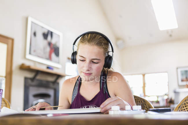 Teenage girl at home wearing headphones as painting — Stock Photo