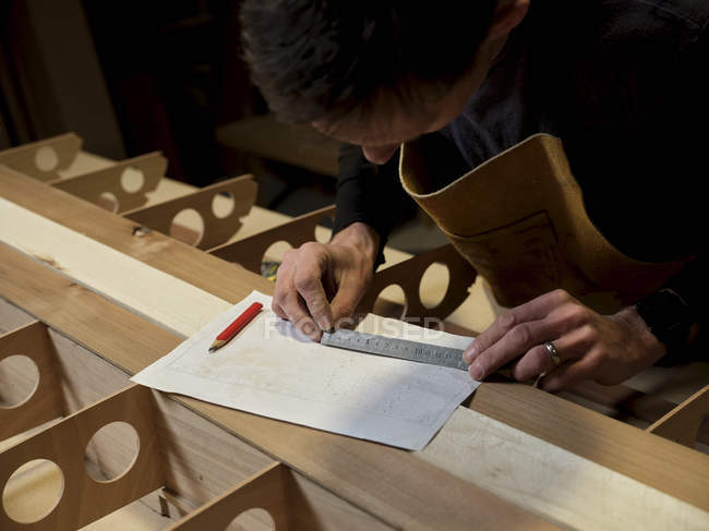 Hombre usando regla de metal en taller de diseño - foto de stock