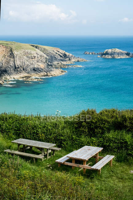 Mesas de picnic de madera en el acantilado en la costa de Pembrokeshire, Gales, Reino Unido . - foto de stock