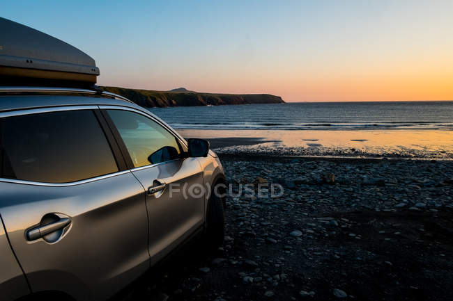 Carro estacionado na praia em Pembrokeshire Coast ao pôr do sol, País de Gales, Reino Unido
. — Fotografia de Stock